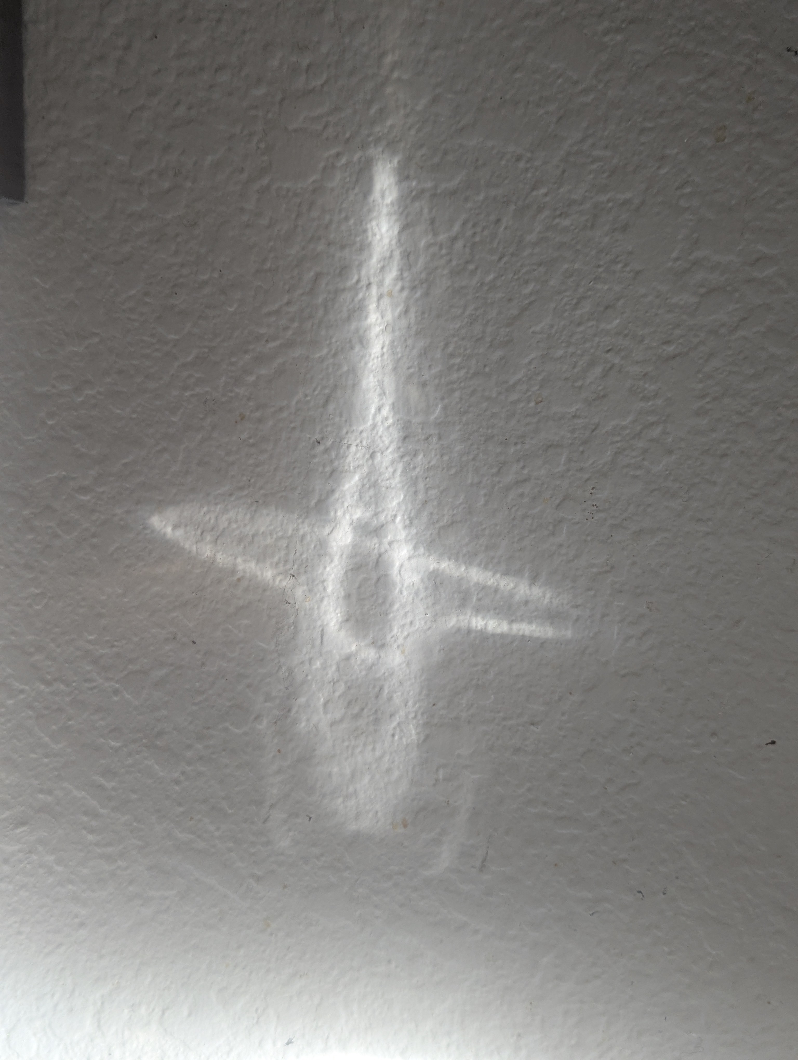 A quiet line of window light crossing a textured wall